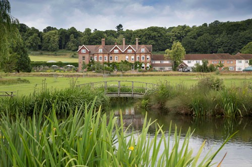 Birtley House Nursing Home from a distance across the Birtley Fishing Lake, with monet style bridge and Surrey woodland behind